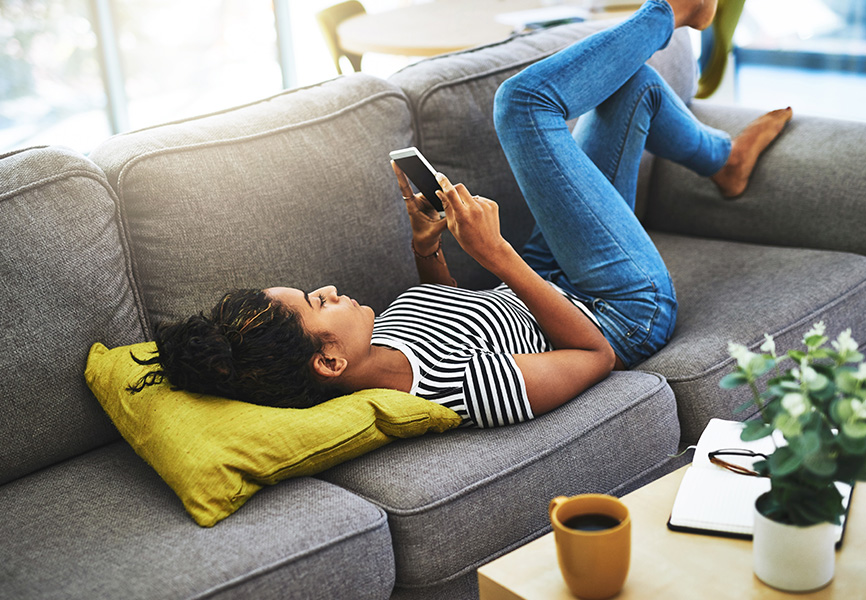 Girl laying on couch scrolling on her phone